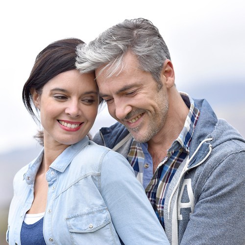Cheerful middle-aged couple embracing outside